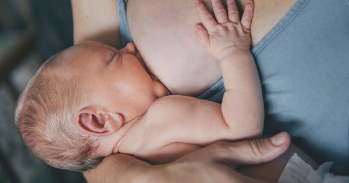 Mother breastfeeding her newborn baby boy. Mom nursing small kid.